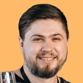 I'm Andrei Anufrienko (-) and I'm pictured here with medium hair with wear glasses which have two colours brown and black. I'm wearing a hoodie. I smile with my mouth open and shout something at the same time, while squinting into the distance. I'm wearing a shirt, a fleece, a T-shirt, and a long-sleeve hooded sweatshirt. The photo is in black, the background is replaced with orange, this is the style of UNICORN WITNESSES brand (unicornwitnesses.com)